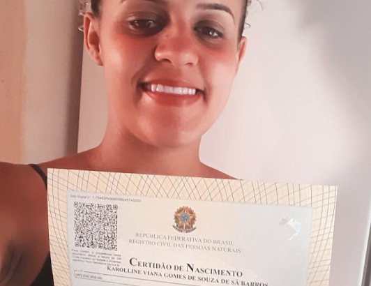 A assistida Karolline Viana Gomes de Souza mostra sua nova certidão, já com o nome do pai incluído, após atuação da DPE/BA
